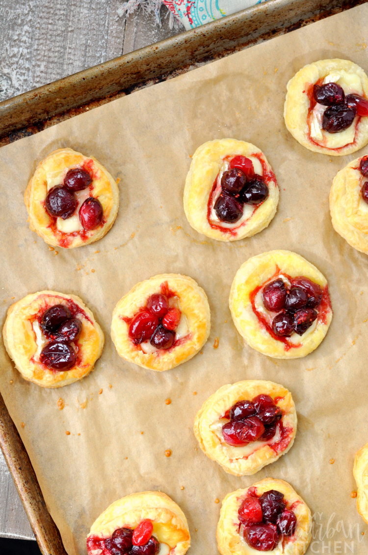 Baked brie cranberry appetizers on parchment paper lined baking sheet