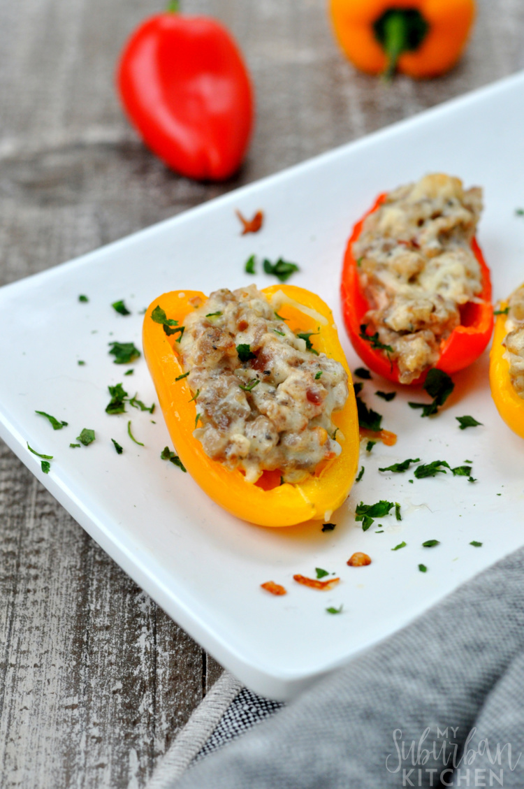Photo of sausage stuffed mini peppers on white serving platter