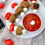 Caprese Meatball Skewers on serving platter with marinara sauce