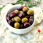 Bowl of warm marinated olives with greenery