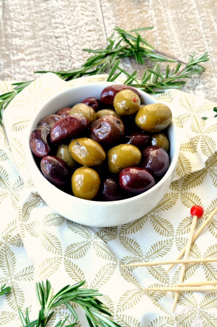Bowl of warm marinated olives with greenery